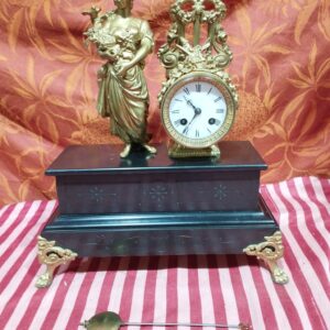 ancienne pendule en marbre noire - décor en régule doré+ balancier + clé -   pieds pattes de lion   décor doré :  femme au bouquet avec oiseau