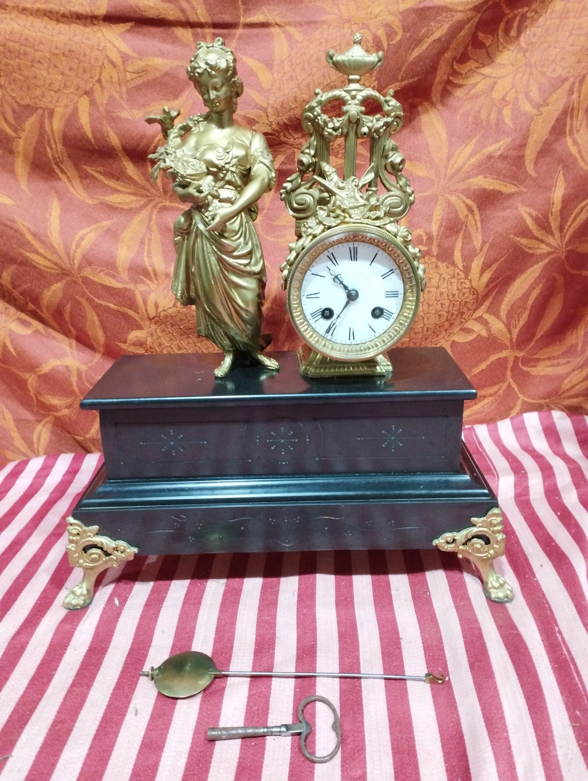 ancienne pendule en marbre noire - décor en régule doré+ balancier + clé - pieds pattes de lion décor doré : femme au bouquet avec oiseau